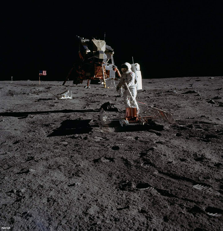 Aldrin deploying the Passive Seismic Experiments Package. In the middle ground is the Lunar Ranging Retroreflector.